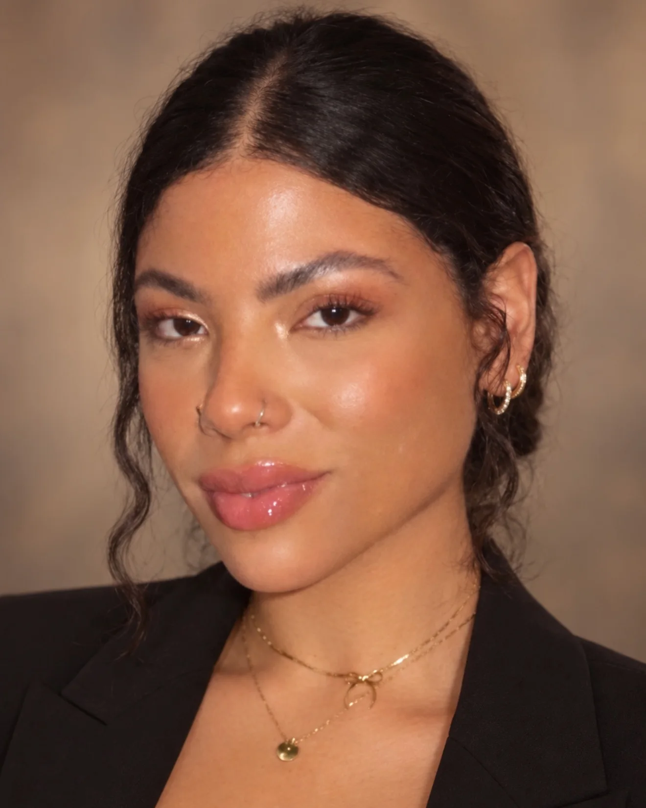 Hanna, esthetician at Lash L’Atelier, with dark hair pulled back, gold earrings and a black blazer